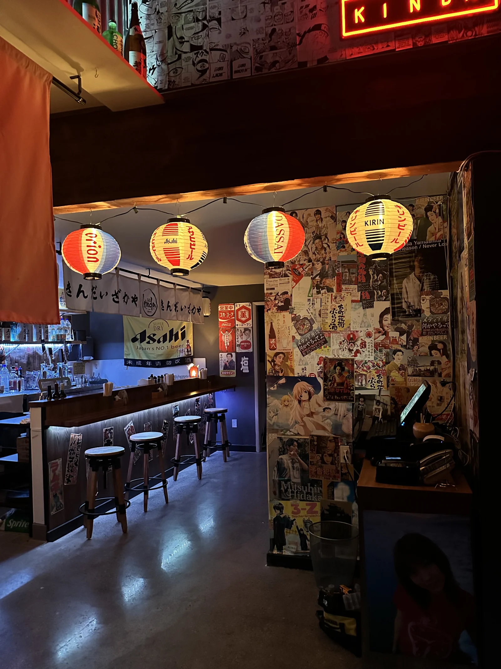 A view into Kinda’s lantern-filled bar with sake bottles, wooden counters and Japanese posters.