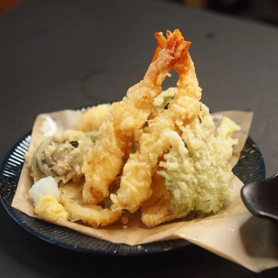 Shrimp and vegetable tempura served on a dark ceramic plate at Kinda Izakaya.