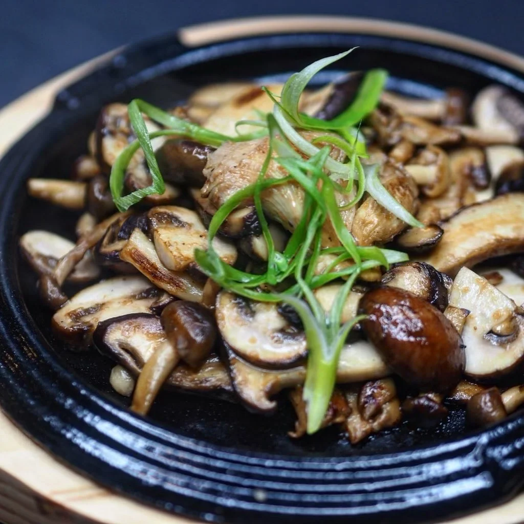Sautéed mushrooms topped with sliced green onions on a blue patterned plate.